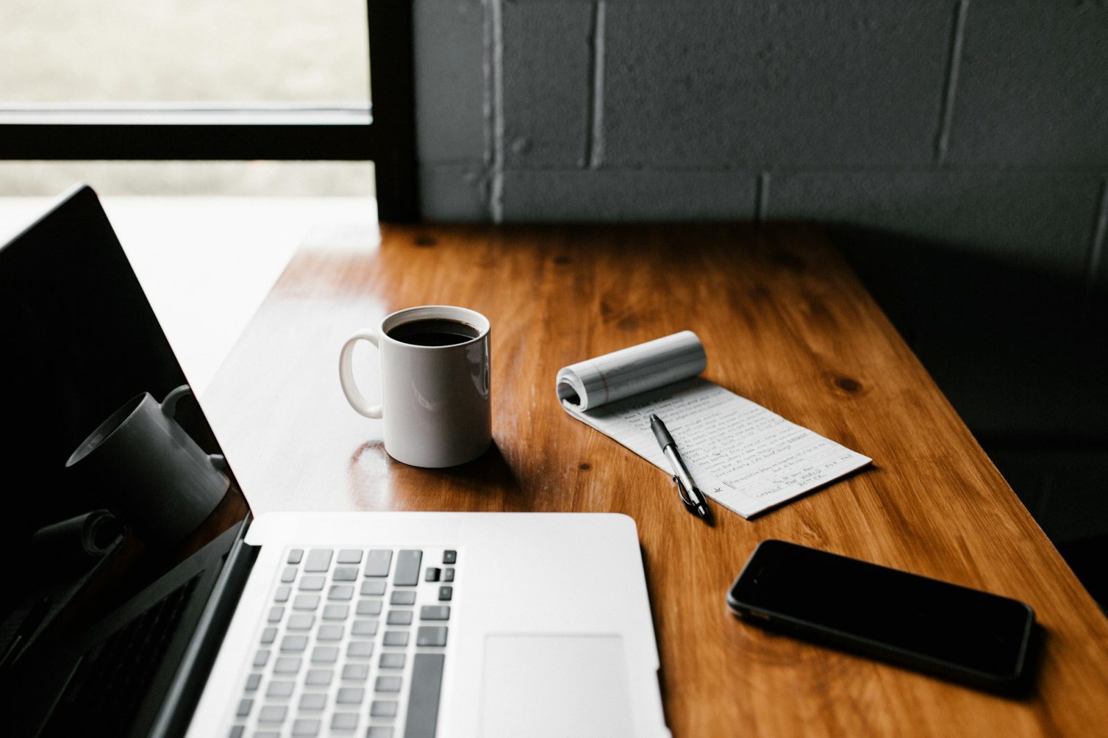 A writing desk with notebook and coffee in morning light